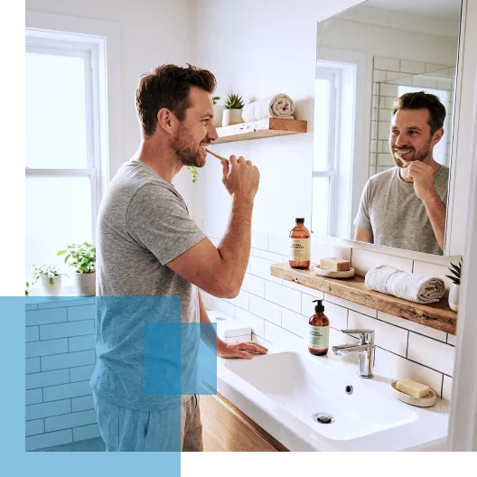 Man brushing teeth in a modern bathroom, looking in the mirror