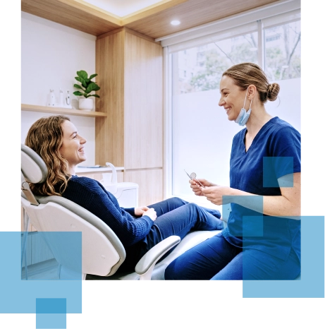 Smiling dental patient sits in a chair while the dentist discusses treatment options.